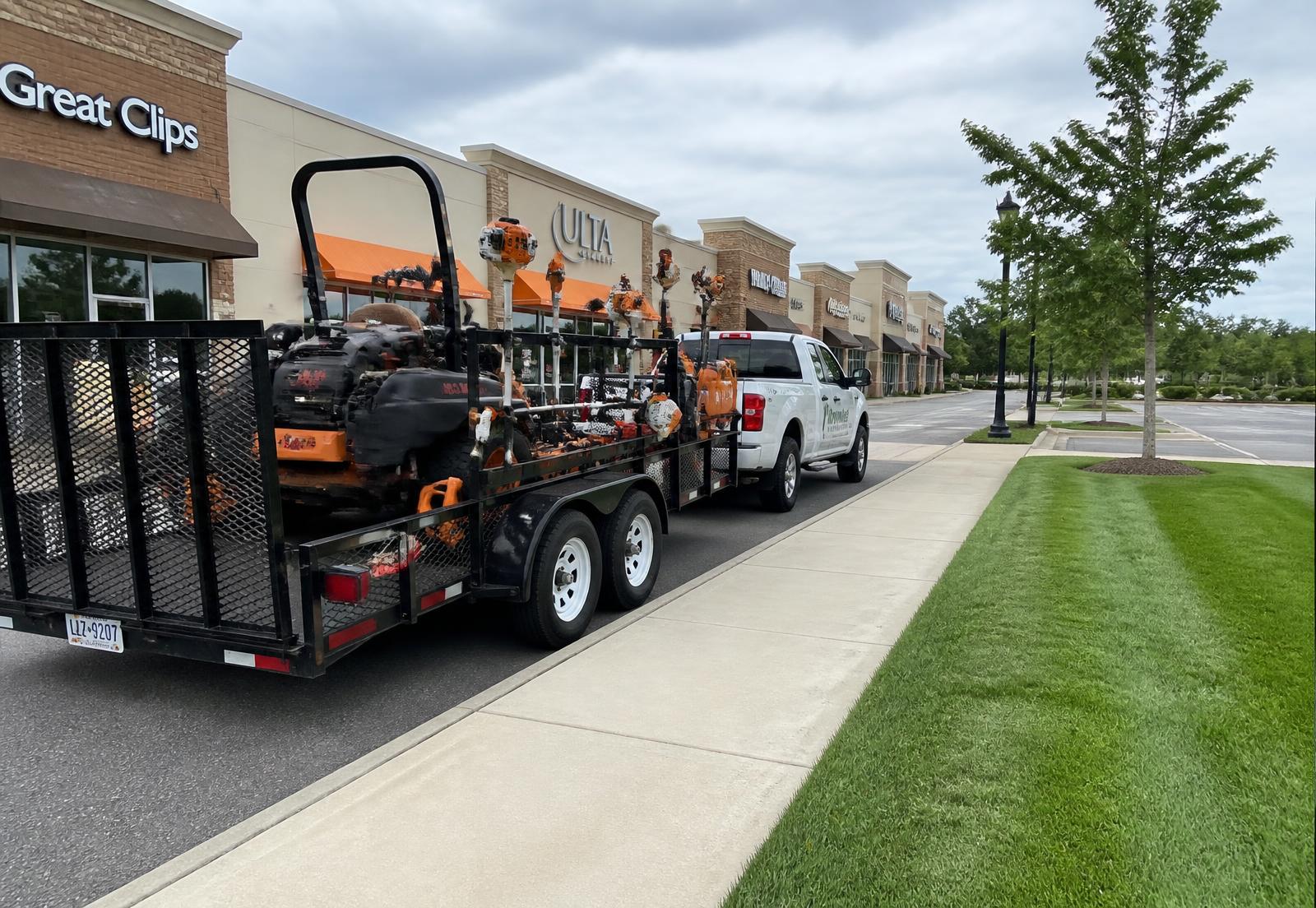 Commercial mowing equipment and trailer parked at a retail plaza before scheduled grounds maintenance